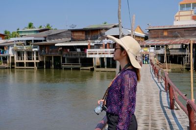 Woman with umbrella in canal against built structures