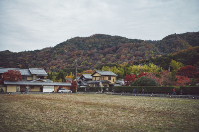 Houses on field by buildings against sky