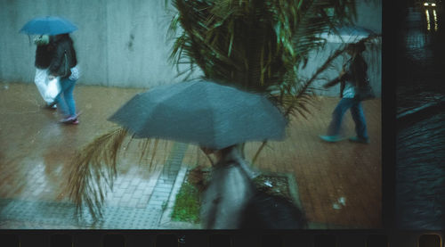 People walking on sidewalk during rainy season