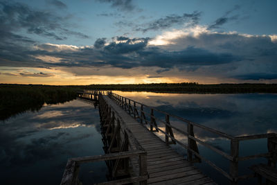 Pier over lake against sky during sunset