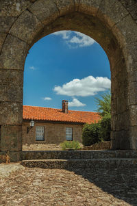 Stone old house and deserted alley seen through wall gate arch at sortelha. portugal.