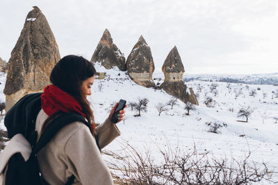 Rear view of woman using mobile phone during winter