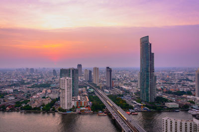 High angle view of river by cityscape against sky during sunset