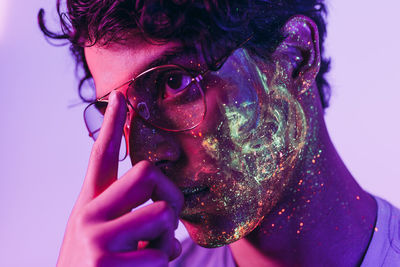 Close-up of man with multi colored face paint wearing eyeglasses