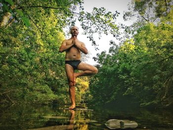 Full length of shirtless man in lake against trees