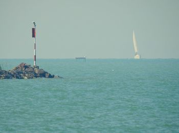 Sailboat in sea against clear sky