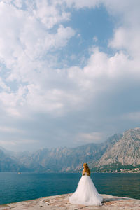 Rear view of woman looking at mountain against sky