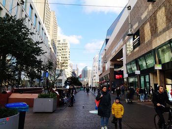 People on street amidst buildings in city