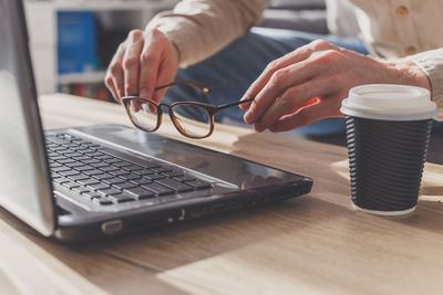 Midsection of man using laptop on table