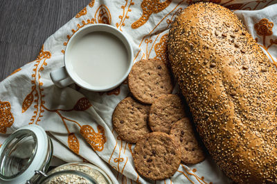 Top view of breakfast with bread, milk, cookies and oatmeal.