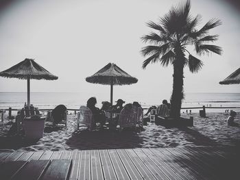 People relaxing on beach against clear sky