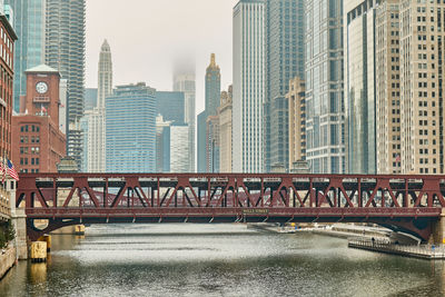 Bridge over river in city against sky