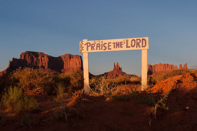 Low angle view of information sign against clear blue sky