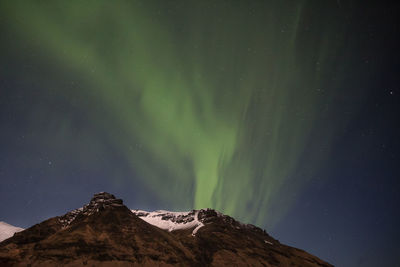 Low angle view of snowcapped mountain against sky at night