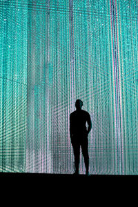 Rear view of silhouette man walking against wall