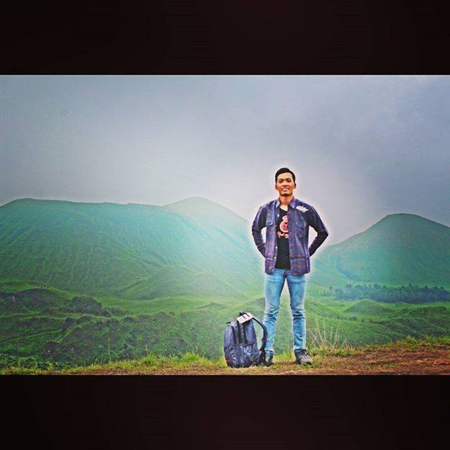 young adult, lifestyles, casual clothing, young men, person, mountain, standing, leisure activity, portrait, looking at camera, full length, three quarter length, front view, smiling, landscape, mountain range, sky