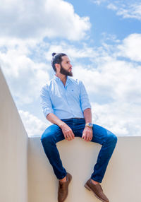 Low angle view of young man standing against sky