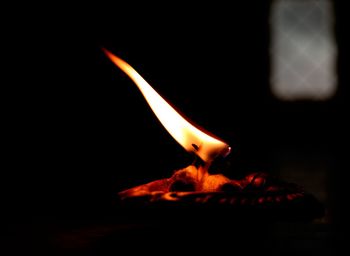 Close-up of lit candle at night