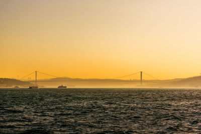 View of suspension bridge over sea during sunset