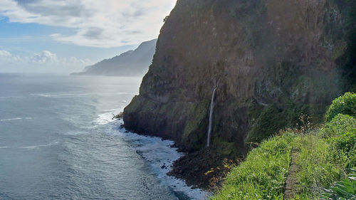 Scenic view of sea by cliff against sky