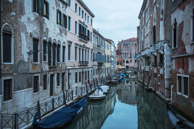 Boats moored in canal amidst buildings in city