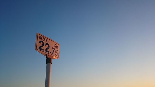 Low angle view of sign board against clear blue sky