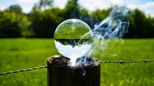 Close-up of crystal ball on wooden post on field