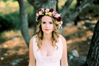 Portrait of smiling young woman standing against trees