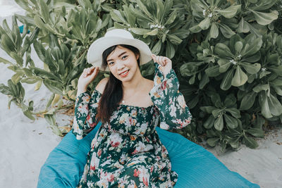 Portrait of smiling woman wearing hat sitting at beach