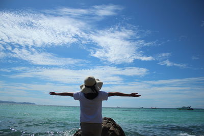 Rear view of man standing in sea against sky