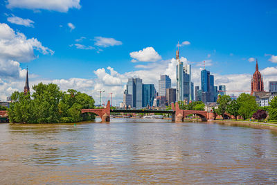 Buildings by river against sky