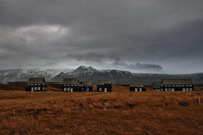 Houses on field against storm clouds