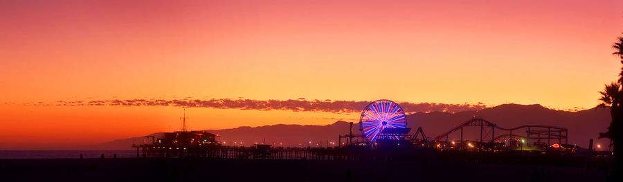 Panoramic view of ferris wheel by santa monica pier against sky during sunset