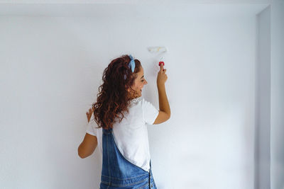 Rear view of woman painting wall at home