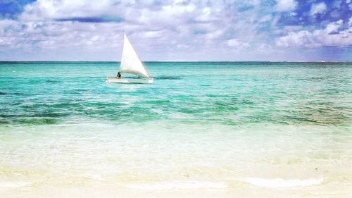 Boat sailing in sea against cloudy sky