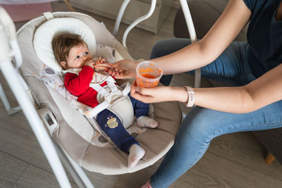 Mother feeding baby girl at home