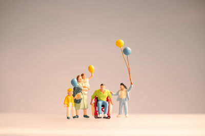 Rear view of people with balloons against gray background