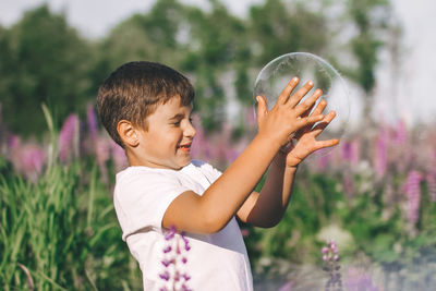 Side view of boy holding purple outdoors