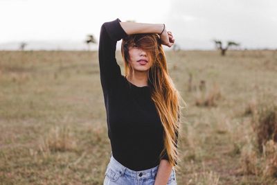 Portrait of young woman standing on field