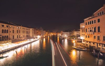Canal amidst illuminated buildings in city at night