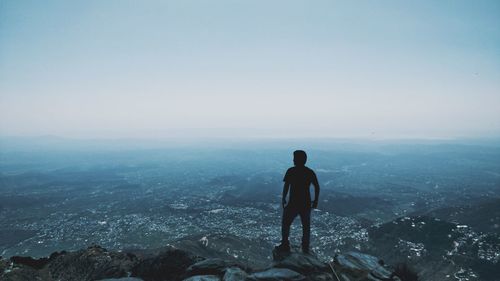 Rear view of man looking at cityscape against sky