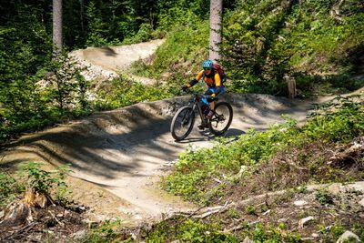 Woman riding a mountain bike on a flow trail in a bike park in glarus, switzerland.