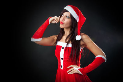 Beautiful young woman standing against black background