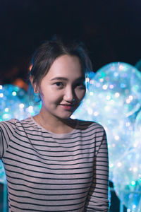 Portrait of young woman against black background