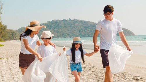 Family with plastic bags walking at beach