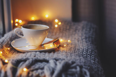 Close-up of drink with illuminated string light on table