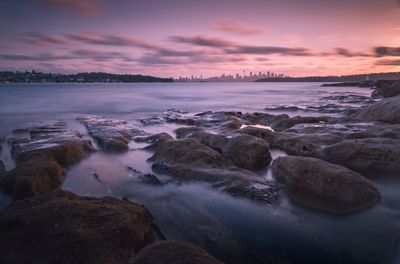 Rocks on beach against sky during sunset