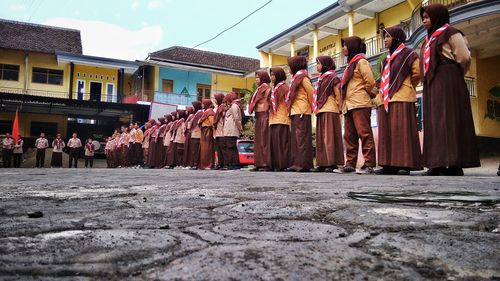 Students standing on footpath against school