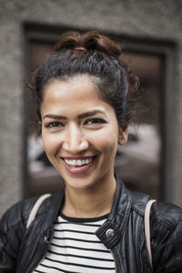 Portrait of smiling woman wearing jacket in city