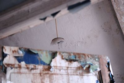 Low angle view of broken pendant light in abandoned house